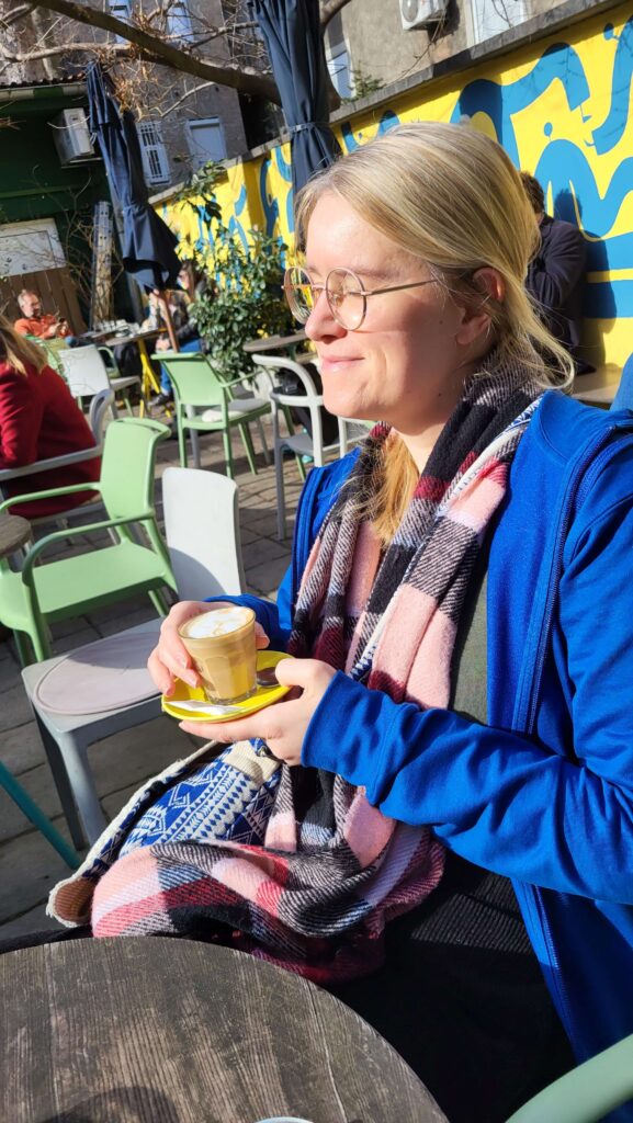 Aleksandra sunbathing and drinking coffee in colourful cafe