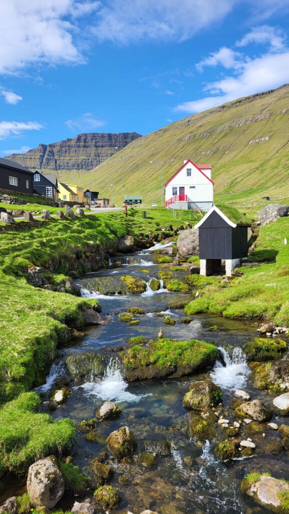 Mountain stream and houses around it in Gjogv