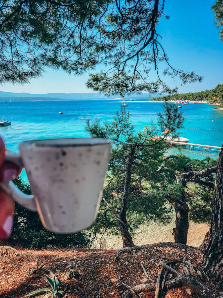 Cup of coffee and the view of sea with turquise waters and beach, Bol in Croatia